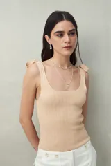 Top tejido blanco con tiras para anudar en los hombros y diseño tramado. Silueta ajustada y textura acanalada.