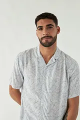 Camisa celeste con estampado de hojas, de corte slim, manga corta, cartera abotonada y logo bordado.