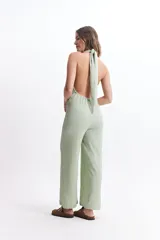 Mono largo color crudo, con escote halter, espalda descubierta y corte palazzo.