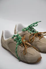 Zapatillas urbanas de cuero color tostado, con cordones verdes y suela de goma.