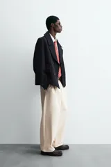 Abrigo corto azul marino de corte relajado, confeccionado en tejido con lana. Tiene cuello con solapas de pico, mangas largas con puños ajustables con trabilla, bolsillos de solapa en la cadera, bolsillo interior, abertura en el centro de la espalda y cierre frontal con botonadura.