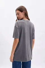 Remera gris oscuro de corte oversize con estampa de un conejo dentro de una corona de flores y la frase "Nature in Harmony" en color rosa.