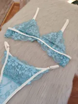 Conjunto de lencería confeccionado en encaje floral color aguamarina con detalles de elásticos en tono champagne. Incluye un corpiño de formato triangular sin aro y una bombacha tipo colaless con breteles regulables.