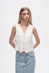 Chaleco blanco sin mangas con cuello en V y cierre frontal con botones.