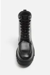 Bota negra de cuero con cordones, suela track y tirador trasero.