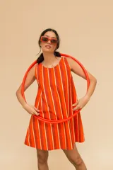 Vestido corto a rayas verticales color naranja, rojo y beige, de corte recto, cuello redondo y sin mangas.