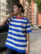 Remerón de mangas cortas con cuello redondo en color rojo y estampado a rayas horizontales azules y blancas. Presenta un pequeño bordado en el pecho.