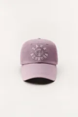 Gorra lila con visera, confeccionada en algodón. Presenta un bordado frontal con el logo "Zara A Coruña" y el texto "Est. 1975". Ajuste trasero con hebilla metálica.