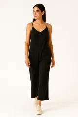 Mono de algodón negro, estilo lencero, con tirantes finos, escote en V y bolsillos frontales. El calce es holgado y presenta un cordón ajustable en la cintura.