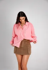 Camisa rosa con detalles de broderie en el frente y mangas globo.