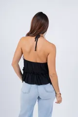 Top rosa con escote halter, volados en el cuello y en el ruedo, y lazo ajustable en el frente.