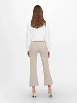 Pantalón tipo calza color beige, de corte flare y tiro alto.