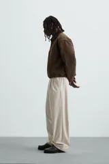 Pantalón de vestir color beige, corte wide fit, con cintura elástica, pliegues frontales, bolsillos laterales y traseros de vivo.