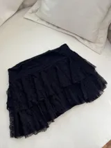 Minifalda negra de encaje con volados escalonados.