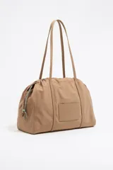 Bolso bandolera grande de nylon color beige, con estructura blanda, doble asa de tejido, logo grabado BIMBA Y LOLA, bolsillo interior con cierre y placa metálica logotipada.