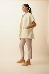 Chaleco color crema de lana sin teñir, corte recto, con cuello y solapa pronunciadas, broches a presión y bolsillos ojal.