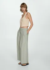 Chaleco color beige con cuello en pico, diseño crop, tirantes anchos y cierre de botón en la parte delantera. Tejido mezcla de lino y lyocell.