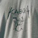 Remera gris con estampado de un baterista y la palabra "Kaboa" escrita a mano.