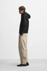 Pantalón chino color verde militar, de corte recto, con bolsillos laterales y traseros de vivo. Cierre frontal con cremallera y botón.