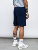 Bermuda deportiva negra de felpa con logo de Umbro bordado en rojo en la pierna derecha.