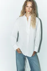 Camisa blanca de corte amplio, con cuello solapa, manga larga y cierre frontal con botones.