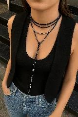 Gargantilla de gamuza negra con tres tiras, dos de ellas con detalles de cuentas plateadas y una con un dije tubular plateado.