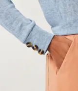 Blusa celeste de viscosa con cuello redondo, mangas largas y puños con botones.