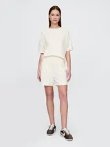 Short deportivo color crema, con cintura elástica ajustable con cordón y logo bordado en la pierna izquierda.