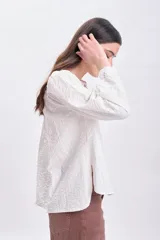 Blusa color crudo con textura, mangas largas abullonadas y cierre frontal con botones.