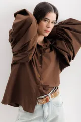 Camisa color beige de algodón con mangas abullonadas y cierre con botones.