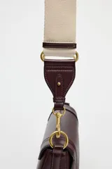 Bolso de hombro ovalado negro con asa de doble tira redonda con detalles metalizados dorados. Cierre imantado y asa de bandolera extraíble con tejido a contraste. Bolso interior con cierre mediante cremallera metálica.
