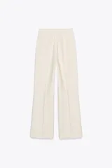 Pantalón palazzo color crema, de tiro alto, con bolsillos laterales y nervio marcado en el frente.