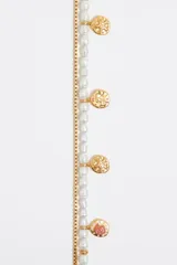 Pulsera dorada de doble cadena, una de eslabones y otra de perlas, con dijes colgantes tipo moneda y cierre de mosquetón.