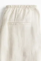 Pantalón de lino color crema, de corte holgado, con cintura elastizada y cordón de ajuste.