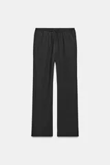 Pantalón negro de tejido fluido, tiro medio, cintura elástica ajustable con cordones y bolsillos laterales ocultos en la costura.