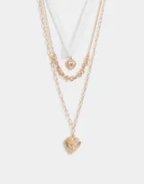 Collar multicadena dorado con tres cadenas de diferentes diseños y dijes de corazones estilo vintage.