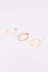 Set de pulseras elásticas con cuentas de colores rosa, blanco y dorado. Incluye dijes de metal dorado con forma de concha y moneda.