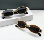 Lentes de sol rectangulares con armazón dorado y patillas negras.