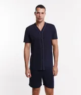 Conjunto de pijama corto azul marino con camisa de manga corta abotonada y short con cintura elástica. Presenta detalle de ribete contrastante en color blanco en el cuello, el frente de la camisa y el ruedo de las mangas.