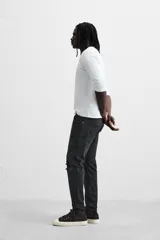 Pantalón de jean negro con corte skinny fit, cinco bolsillos, lavado con efecto roto y cierre frontal con cremallera y botón.