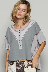 Remera gris de manga corta con escote en bote y abotonado, corte oversize y estilo patchwork en dos telas.
