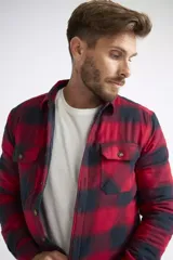 Sobrecamisa de viyela para hombre con estampado de cuadros en rojo y negro. Presenta cierre frontal con botones, bolsillos en el pecho con solapa y botón, y un interior capitoneado para mayor abrigo. Cuenta con un logo en grifa de cuero.