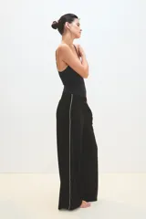 Pantalón palazzo negro con cintura elástica y una fina línea blanca vertical en los laterales.