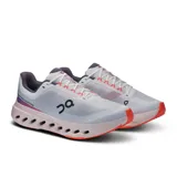 Championes de running blancos con detalles en gris y naranja, marca On Cloudsurfer Next.