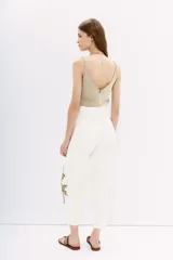Pantalón blanco de tiro alto con corte paper bag, cintura con lazo a tono y bordado con lentejuelas y piedras en el lateral.