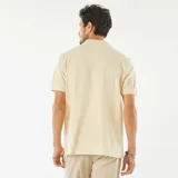 Remera tipo polo color crema, de piqué de algodón, con cuello clásico, tapeta de dos botones y mangas cortas con ribete.
