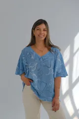 Blusa celeste con estampado de flores blancas y azules, de corte amplio y mangas cortas.