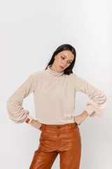 Polera de plush color blanco con cuello alto y mangas largas abullonadas.