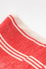 Lona de playa rectangular con diseño estampado a rayas rojas y blancas.