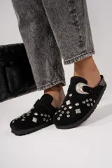 Suecos negros de cuero gamuza con apliques de tachas plateadas y hebilla decorativa.